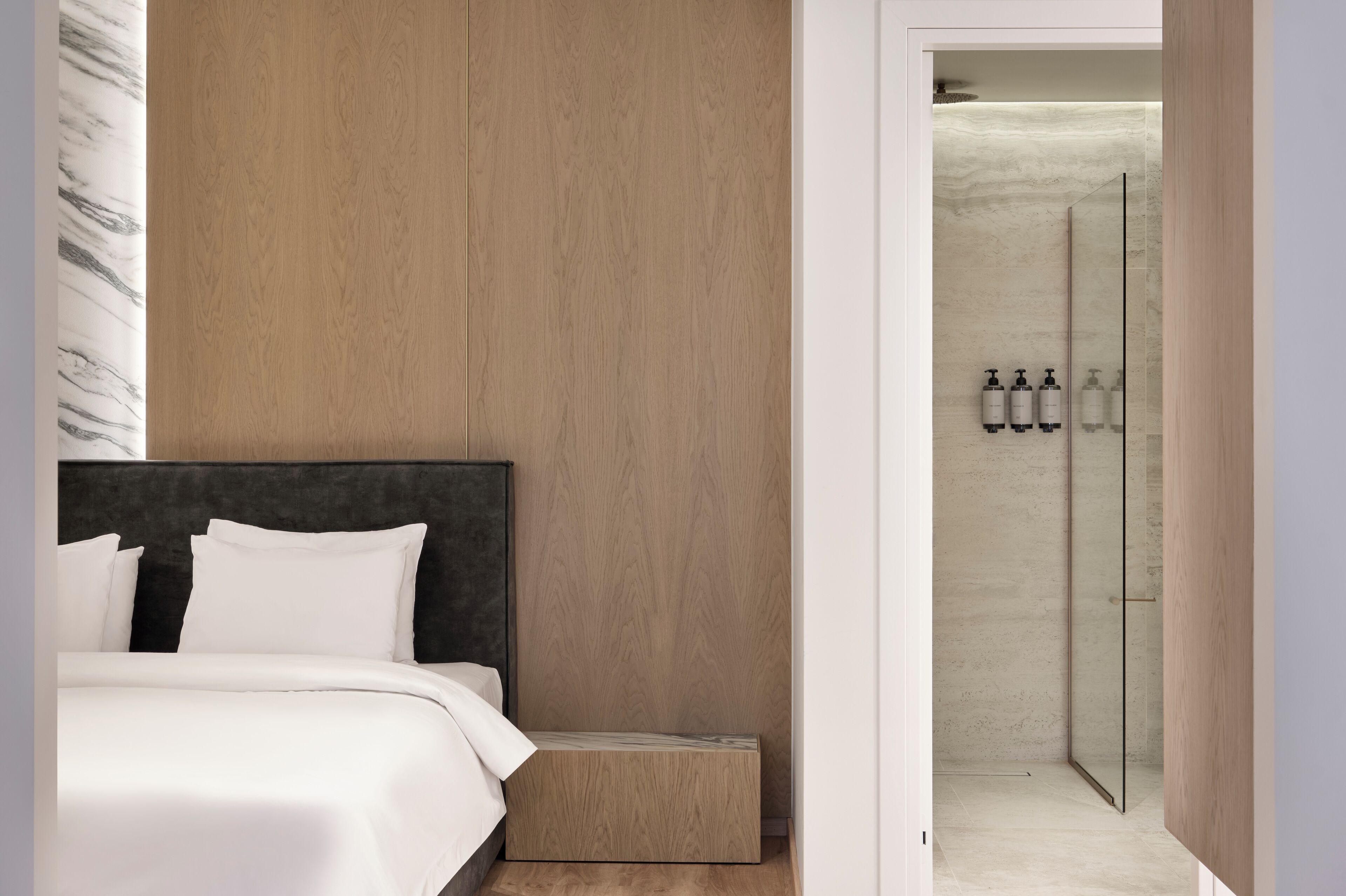 Una camera da letto moderna con una testiera in legno, un comodino e una cabina doccia in vetro.