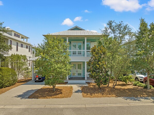 A two-story building with a balcony, surrounded by trees and a paved driveway. - Aquamarine in The Preserve at Grayton - Included Golf Cart, Close to Pool! (Santa Rosa Beach)