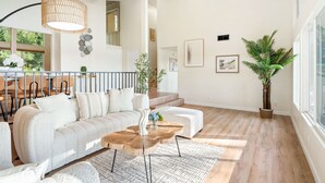 A spacious living room with a sofa, coffee table, and a large window. - Spacious Retreat With Scenic Mountain Views (Santa Ana)