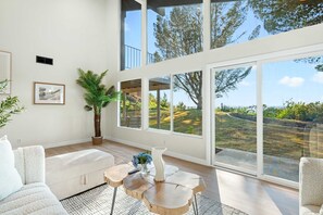 A spacious living room with a large window, a sofa, a coffee table, and a potted plant. - Spacious Retreat With Scenic Mountain Views (Santa Ana)