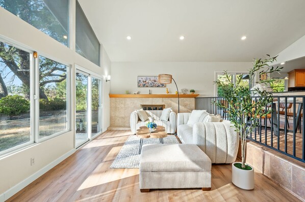 A spacious living room with a large window, a fireplace, a sofa, and a coffee table. - Spacious Retreat With Scenic Mountain Views (Santa Ana)