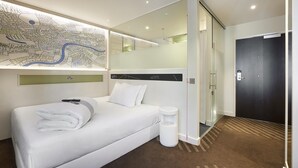 Una camera d'albergo con un letto grande, una mappa appesa al muro, una moderna testiera e una porta con maniglia.