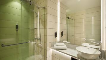A modern bathroom with a glass-enclosed shower, a vanity with a sink, and a large mirror.
