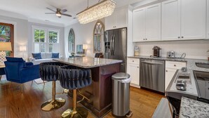 Una cocina moderna con armarios blancos, electrodomésticos de acero inoxidable y una barra con taburetes.