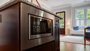 Una cocina con horno empotrado y microondas, armarios de madera y encimera de granito.