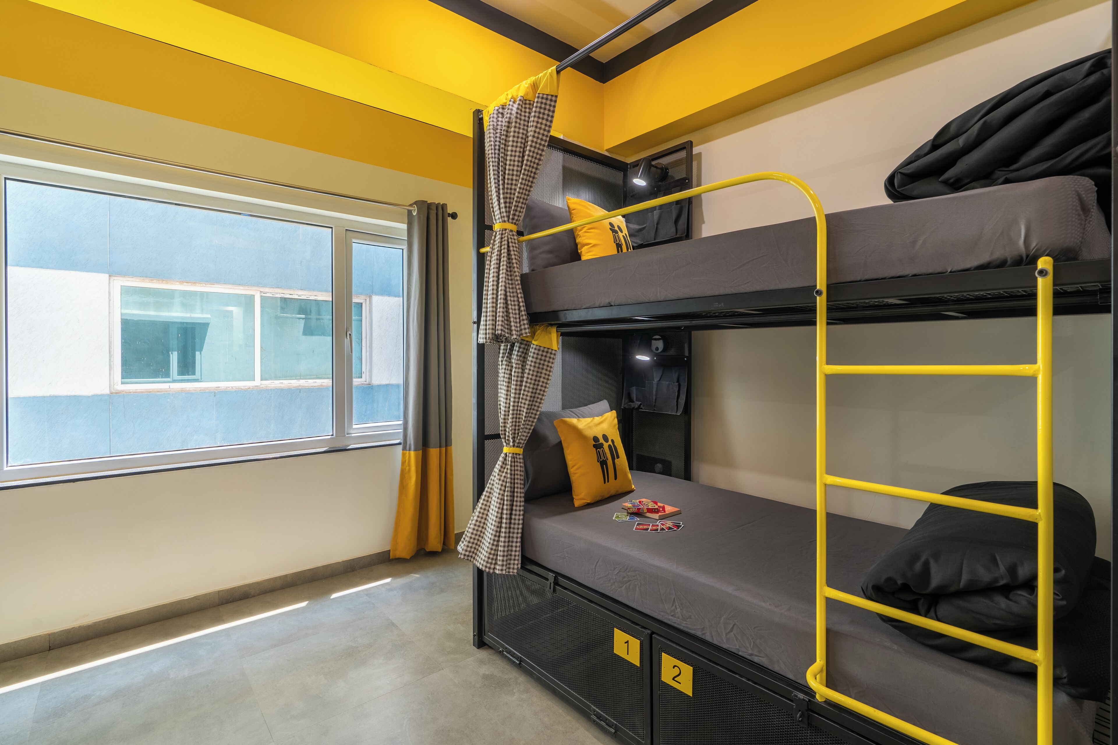 A bunk bed room with a window, curtains, and numbered storage compartments.