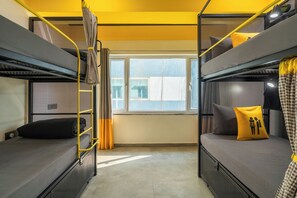 Una camera del dormitorio con letti a castello, una finestra con tende e vista all'esterno.