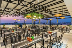 Un ristorante all'aperto con tavoli e sedie, una pianta pensile verde e vista sulla città.