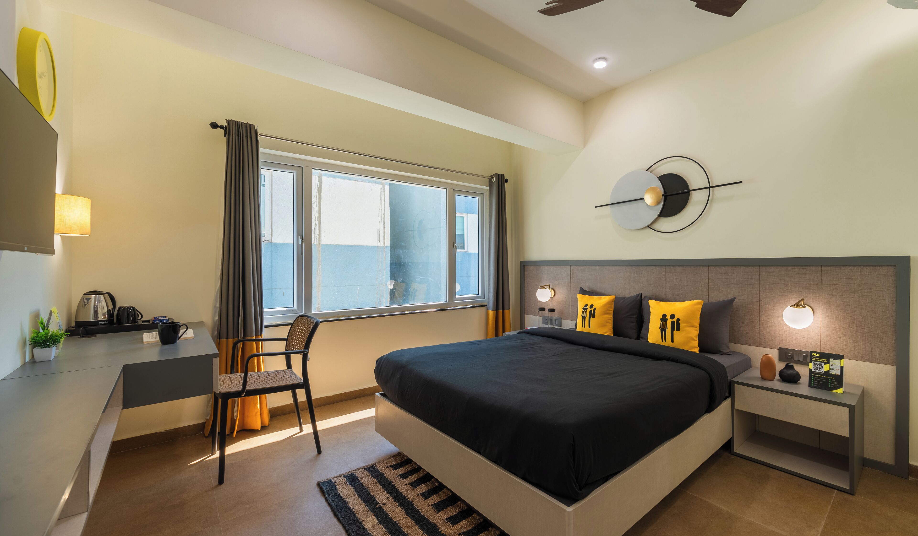 A modern hotel room with a large bed, bedside tables, a desk, and a chair.