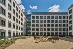 A courtyard with outdoor seating, a building with multiple windows, and a clear sky. - The Carabanchel Episode (Madrid)