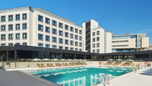 A modern hotel with a swimming pool, sun loungers, and umbrellas. - The Carabanchel Episode (Madrid)