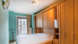 Une chambre à coucher avec un lit, une armoire en bois et une fenêtre avec des rideaux.