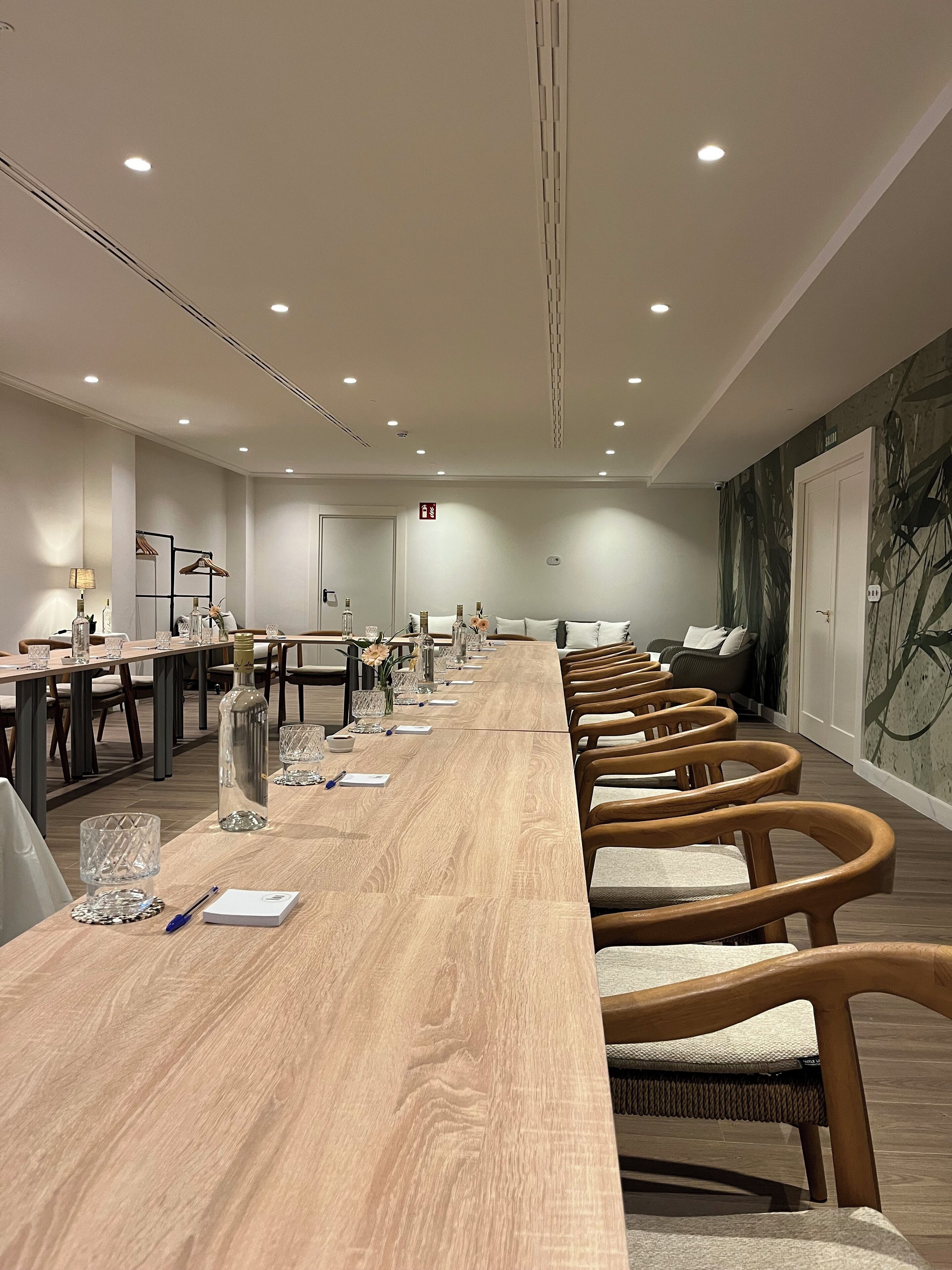 Una sala de conferencias con una larga mesa de madera, varias sillas y un papel tapiz estampado.