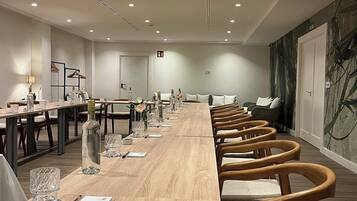 Una sala de conferencias con una larga mesa de madera, varias sillas y un papel tapiz estampado.