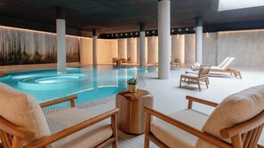 Una piscina techada, sillones reclinables de piscina