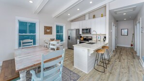 A modern kitchen with white cabinetry, a central island, and bar stools. - Private Pool | Pet Friendly | Sleeps 10 | Gulf Views (Cape San Blas)