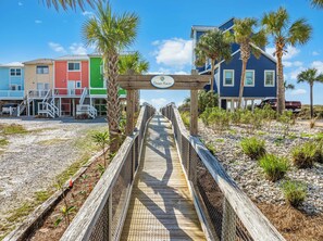 A wooden boardwalk leading to a beach house with a sign reading "Ocean Haven."