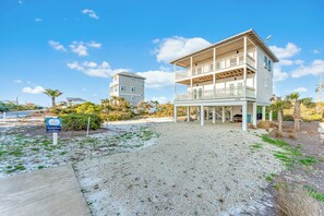 A beachfront hotel with a two-story structure, a covered porch, and a visible address sign.