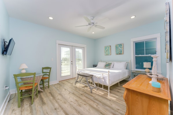 A bedroom with a bed, a ceiling fan, a window, and a door.