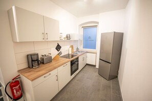 A compact kitchen with white cabinets, a wooden countertop, a stainless steel refrigerator, and a window with a view. - RR | Spacious Apt_2-67 m²| Parking | Central (Magdeburg)