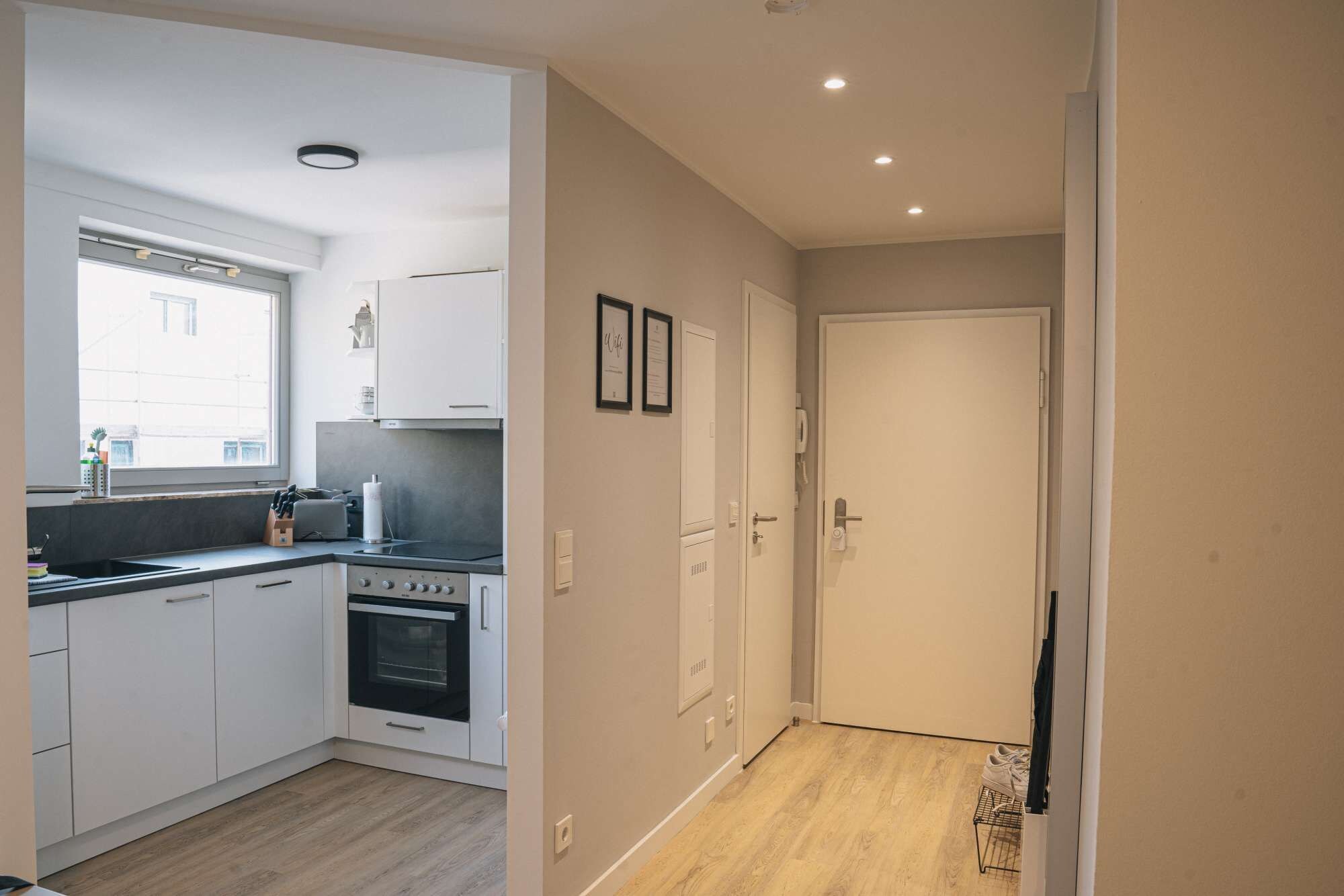 A modern kitchen with white cabinets, a built-in oven, and a window.