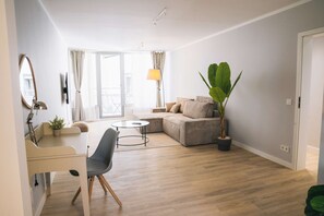 A modern living room with a sofa, a coffee table, a chair, and a large plant.