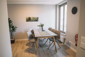 Un coin repas avec une table, des chaises, une plante et une horloge au mur.