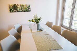 Un salón de conferencias con una larga mesa, sillas, un jarrón con flores y un menú sobre la mesa.