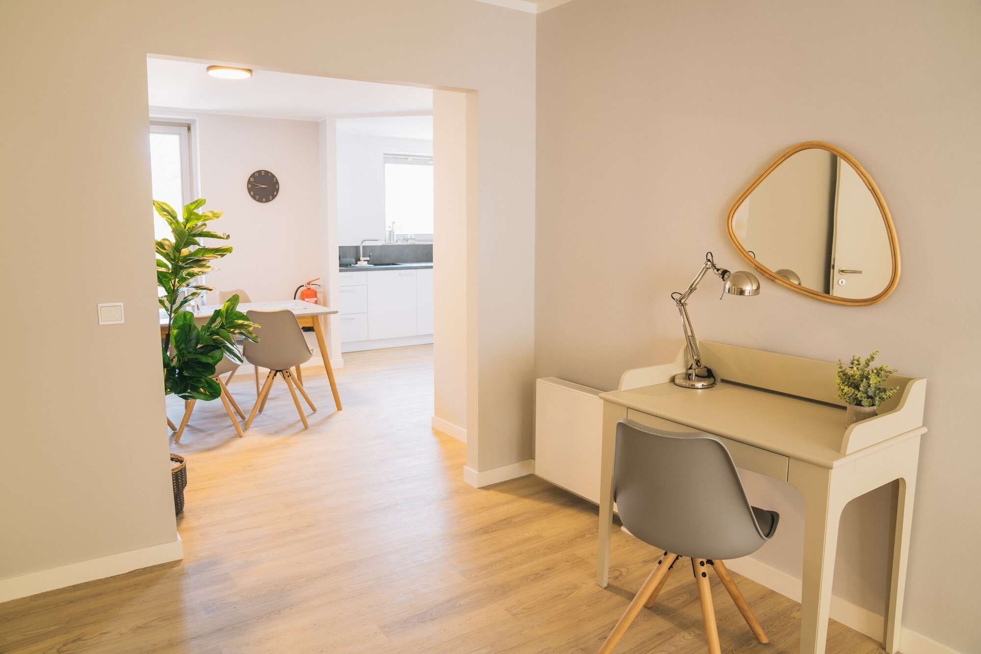 A modern interior with a desk, chair, and a round mirror on the wall.