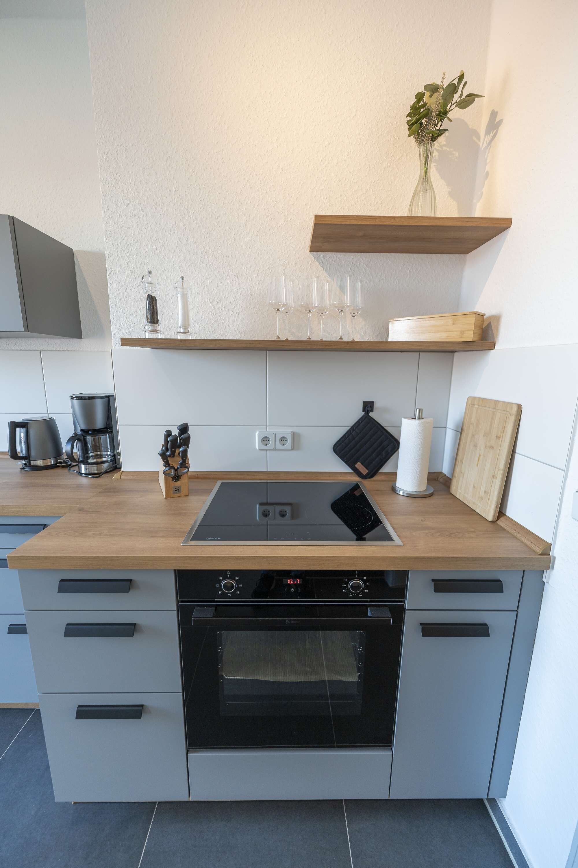 Een moderne keuken met een inbouwoven, een kookplaat en een houten aanrecht.
