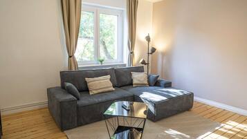 Uma sala de estar moderna com um sofá seccional, uma mesa de centro de vidro e um abajur.