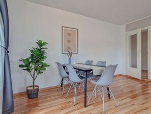 Un coin repas avec une table et des chaises, une plante en pot et une œuvre d’art encadrée accrochée au mur.
