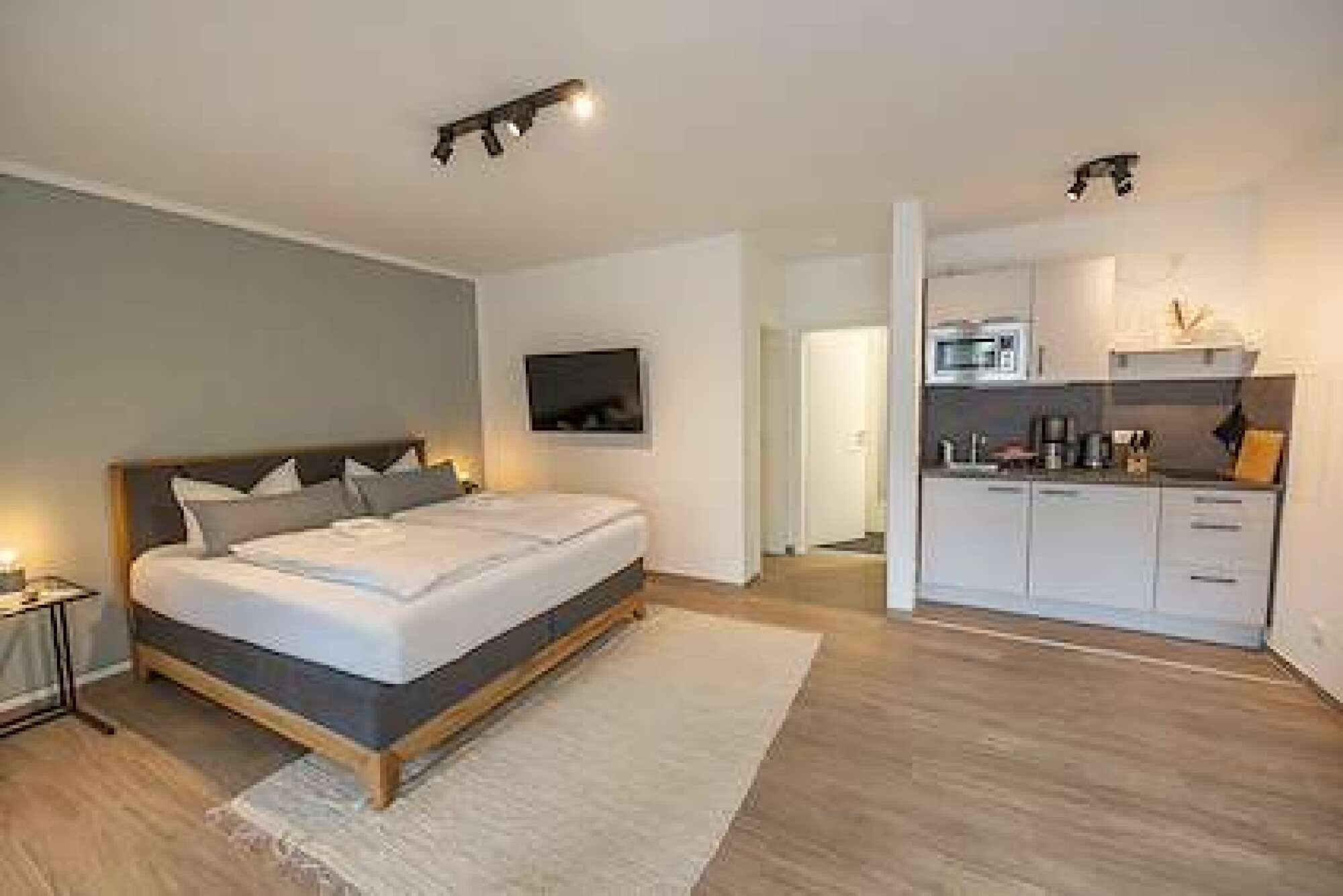 Ein modernes Schlafzimmer mit einem großen Bett, einem Nachttisch und einem wandmontierten Flachbildfernseher.