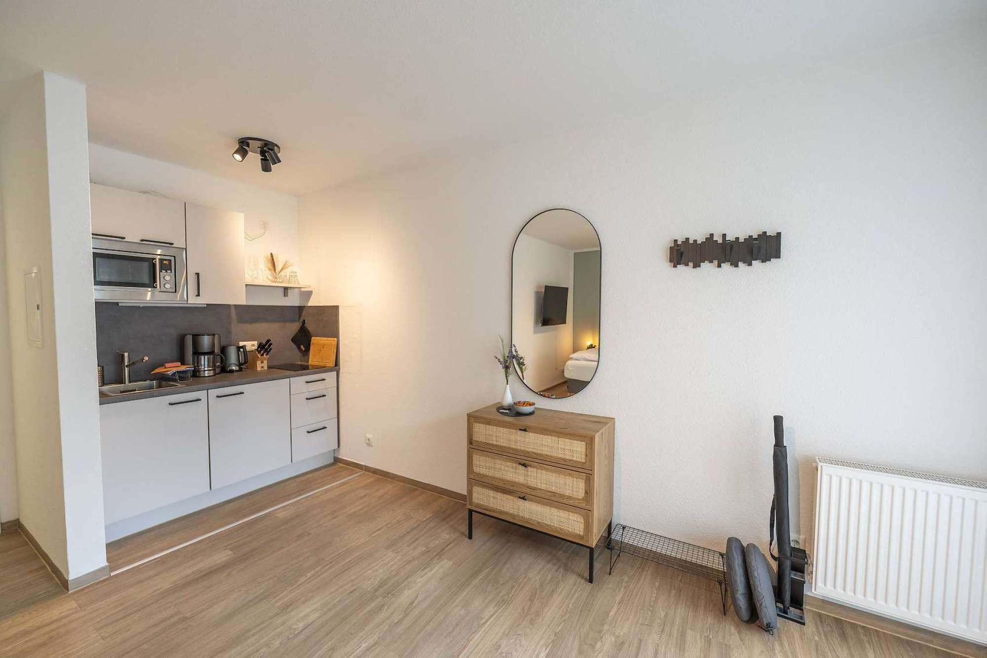 Een moderne keuken met een magnetron, koffiezetapparaat en een houten kast.
