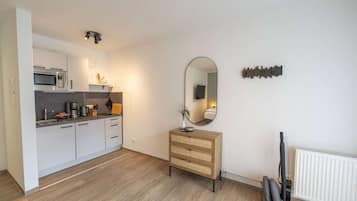 Een moderne keuken met een magnetron, koffiezetapparaat en een houten kast.