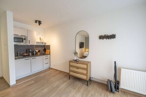 A modern kitchen with a microwave, coffee maker, and a wooden cabinet.