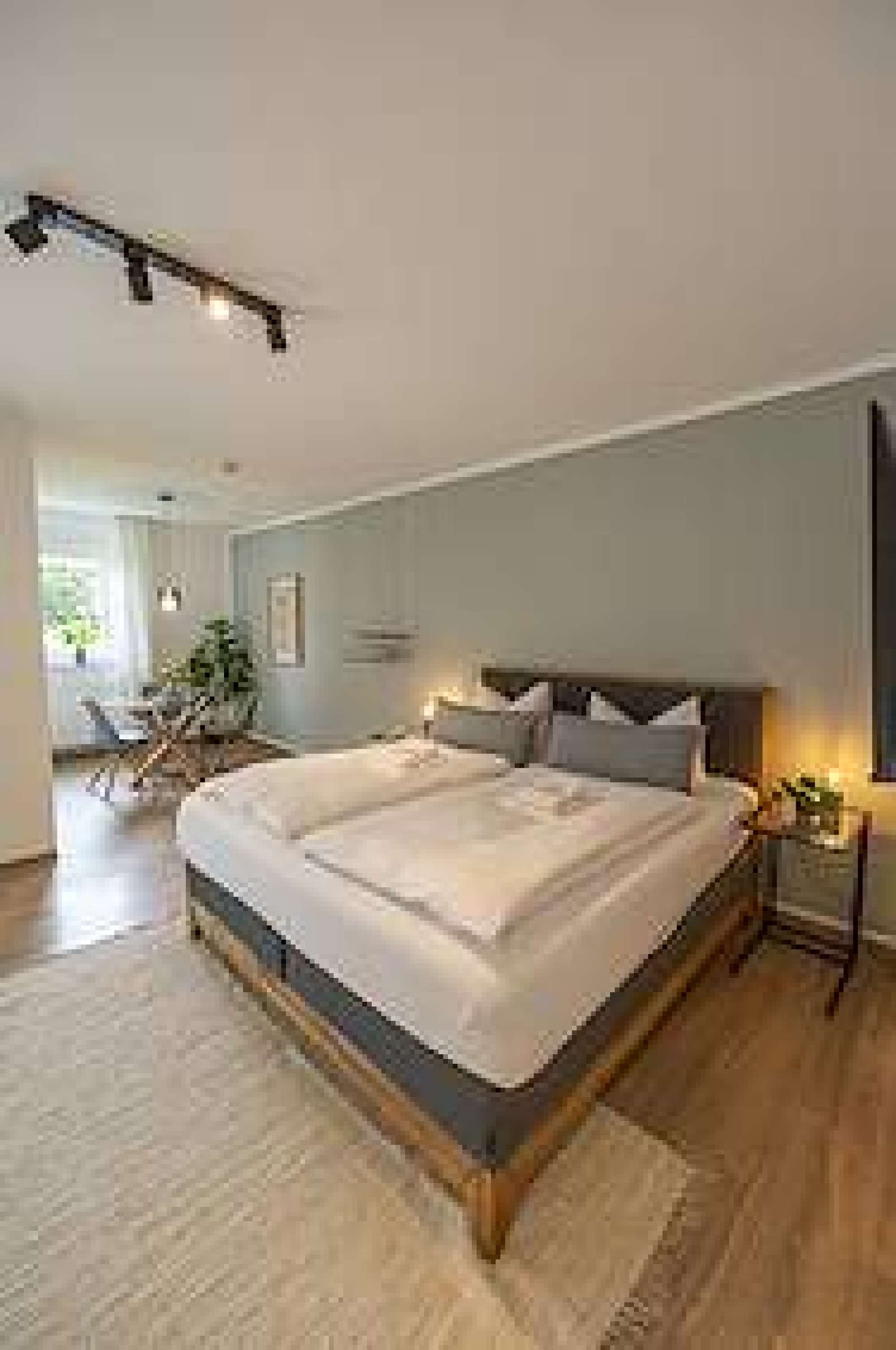 Een slaapkamer met een groot bed, een nachtkastje en een raam.