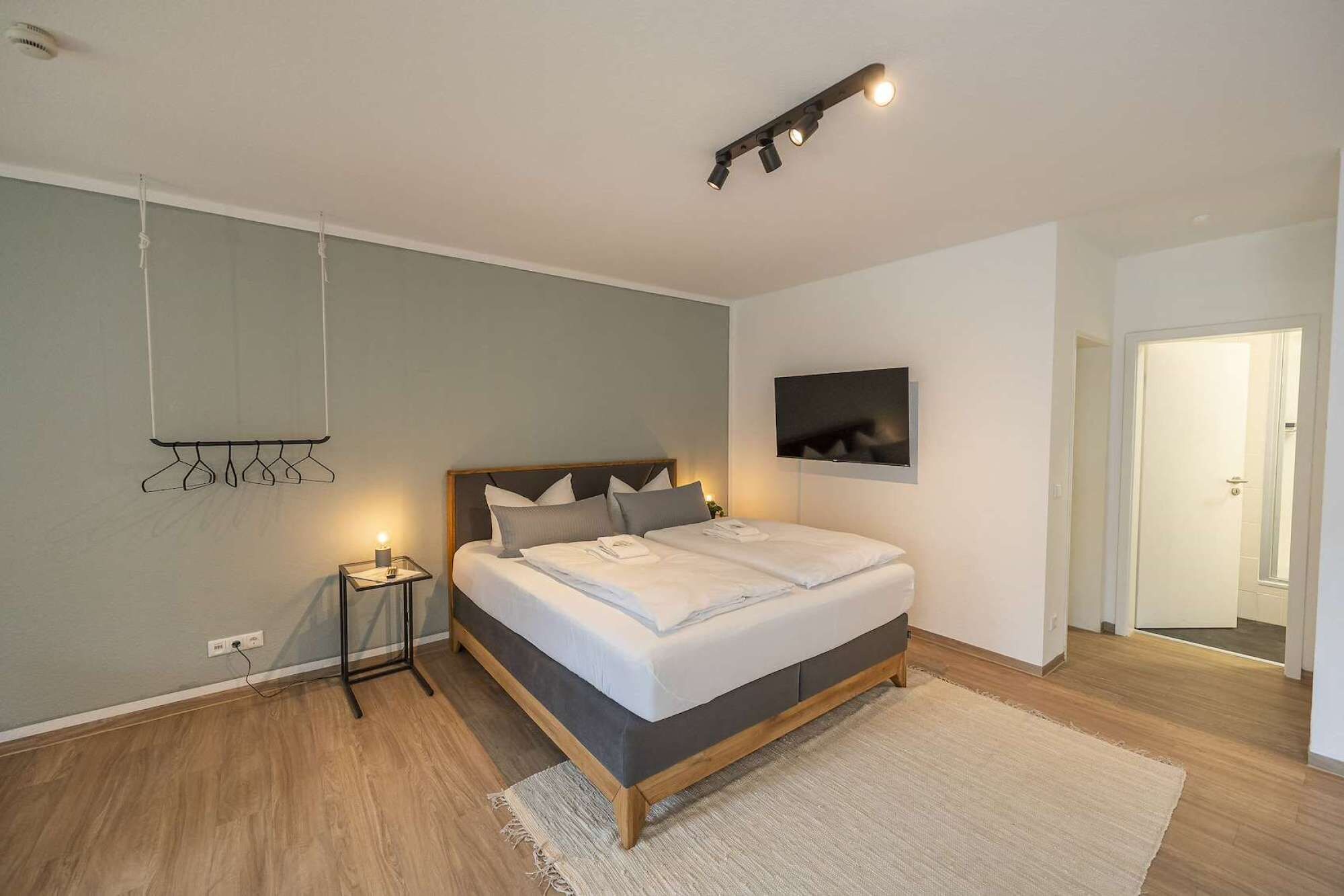 Een moderne slaapkamer met een bed, nachtkastje en een televisie aan de muur.