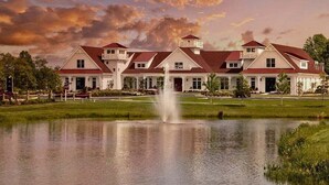A large, multi-story building with a symmetrical facade, a central water feature, and a well-maintained lawn.