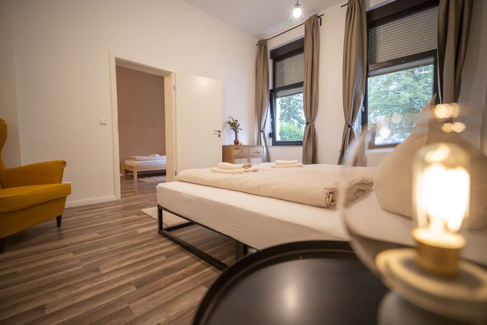 Een moderne slaapkamer met een bed, een stoel en een nachtkastje met een lamp.