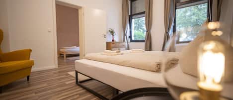 Een moderne slaapkamer met een bed, een stoel en een nachtkastje met een lamp.