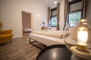 Un dormitorio moderno con una cama, una silla y una mesita de noche con lámpara.