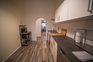 A modern kitchen with a central island, wooden flooring, and white cabinetry. - RR | Spacious Apt_1-70 m² | Parking | Central (Magdeburg)