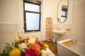 Un baño moderno con ventana, un lavamanos, un espejo y una estantería de madera.