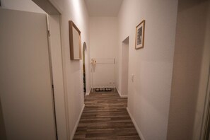 A narrow hallway with wooden flooring, white walls, and a door at the end. - RR | Spacious Apt_1-70 m² | Parking | Central (Magdeburg)
