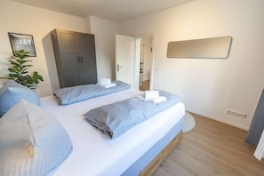 Una habitación de hotel con dos camas, un armario, un espejo y una planta en maceta.