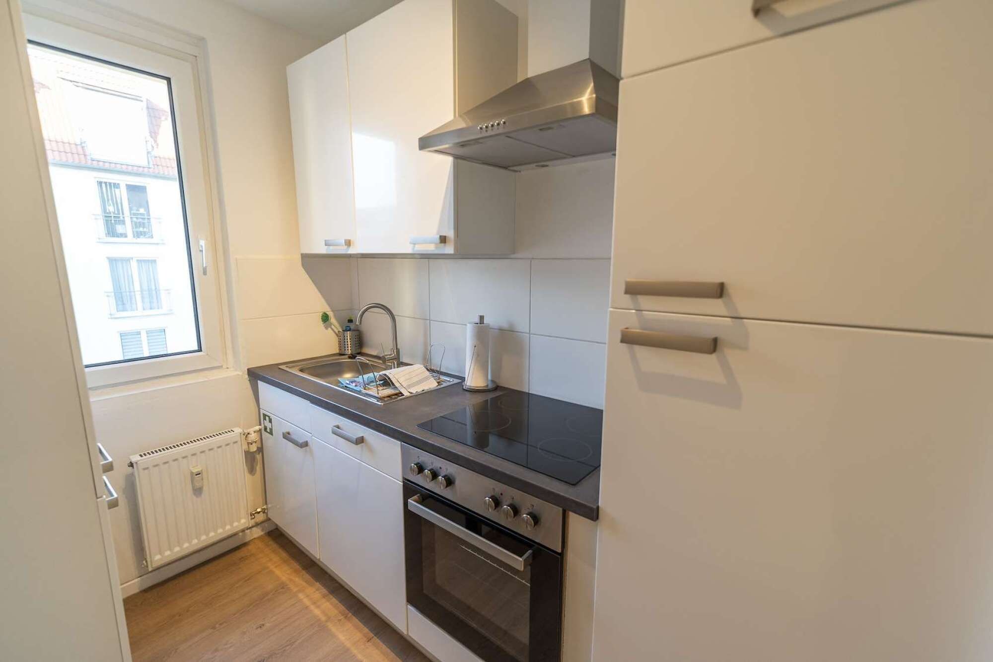 A compact kitchen with a built-in oven, a stovetop, and a window providing natural light.