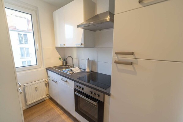 Cocina compacta con horno empotrado, estufa y ventana que proporciona luz natural.