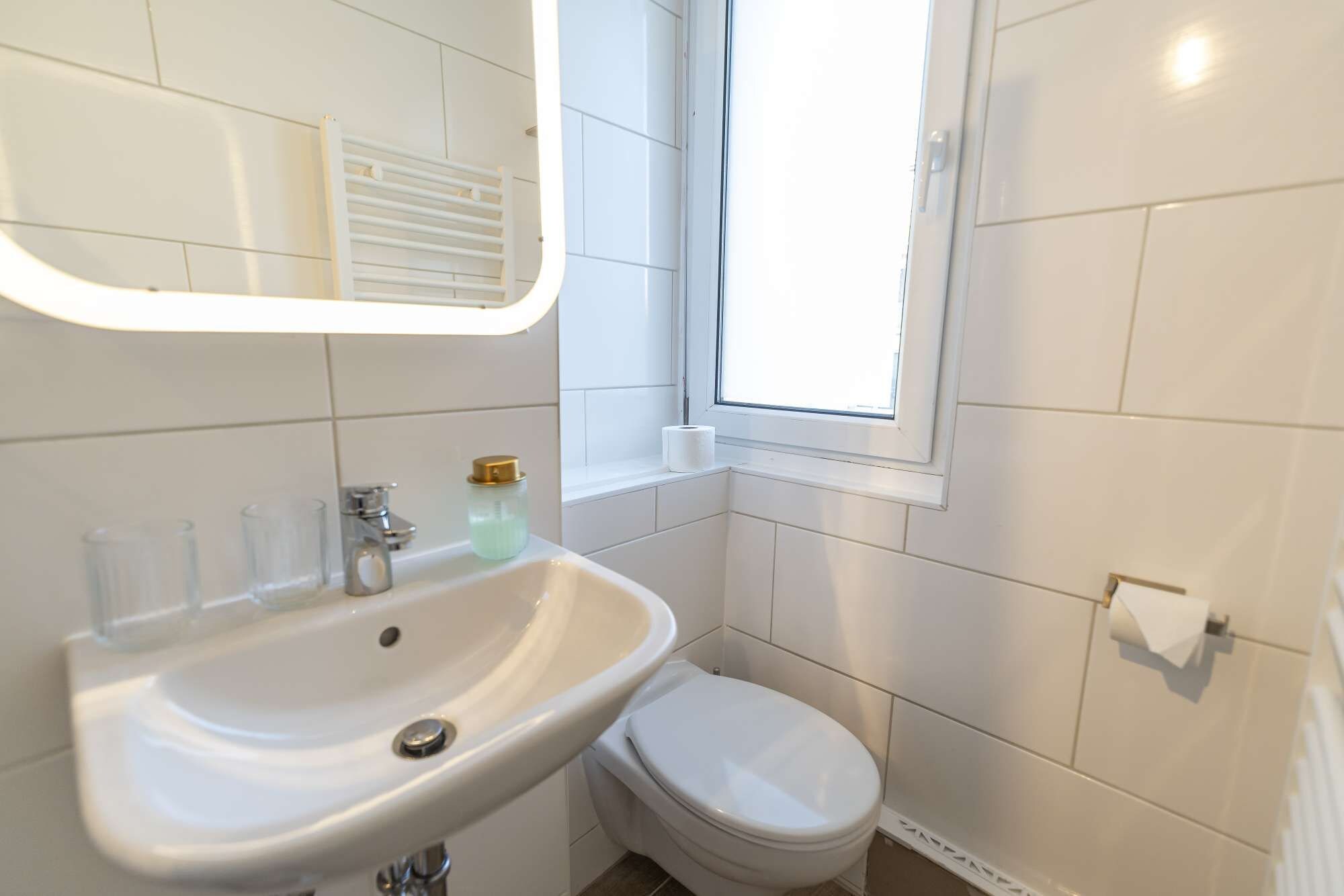 A bathroom with a white sink, toilet, and a window.