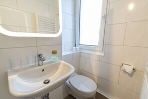 Un baño con lavamanos, inodoro y ventana.
